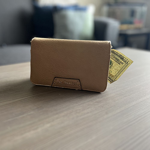 Beige wallet sitting on a table with money sticking out of it